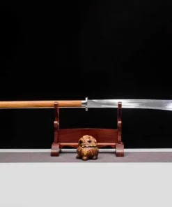 A Chinese Guandao weapon with a long wooden handle, displayed on a small stand.