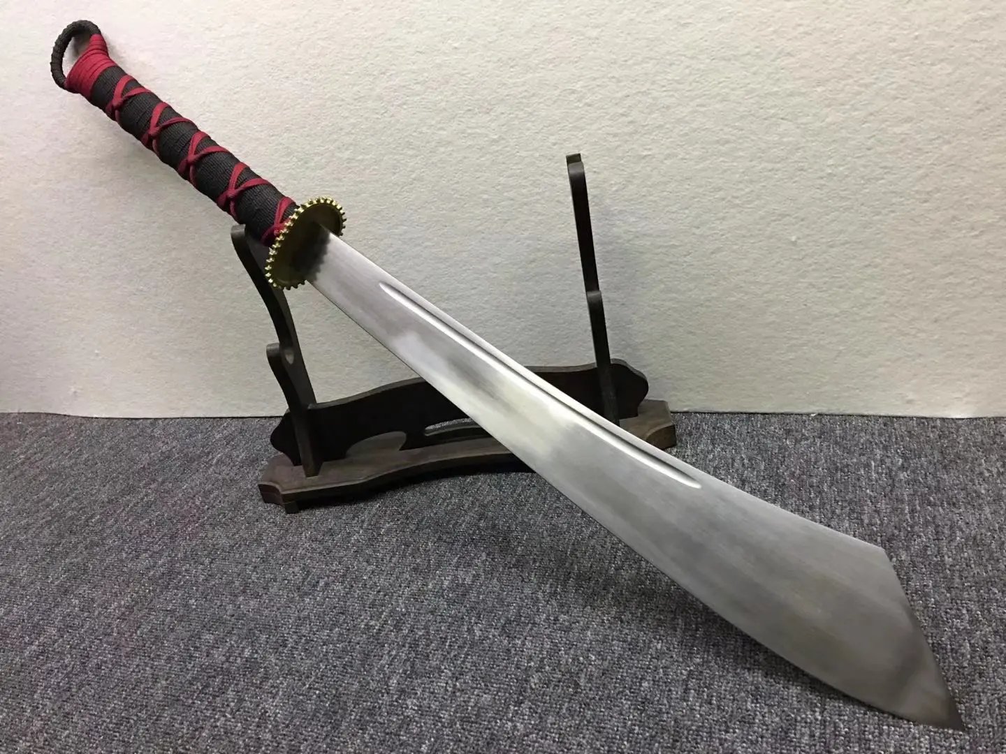 Kandao A Kandao Chinese broadsword leaning against a small wooden stand.