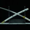 A Katana anime sword displayed crossed against its scabbard, on a small sword stand.