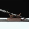 A one handed spear with a double edged spearhead, leaning on a small wooden stand.