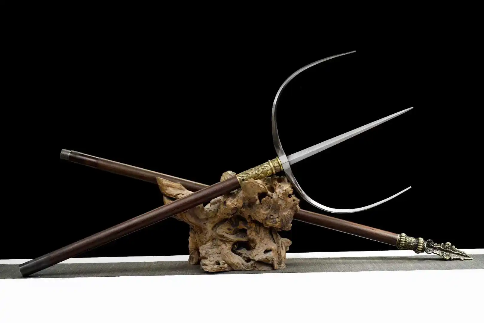 Tiger Fork A Chinese tiger fork weapon, displayed next to its handle attachment, on a small wood log.