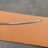 A Wakizashi blade blank, lying on a sheet of cardboard, on the floor.