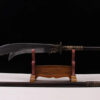 A Kwan Dao weapon displayed on a wooden-stand, with its handle extension on the floor below.