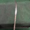 A naginata blade blank displayed against a green floor.