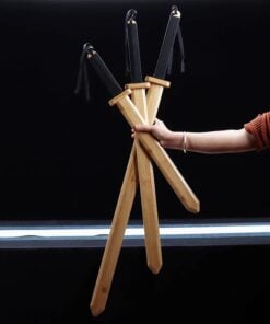 A mans hand holding three different sized wooden toy swords.