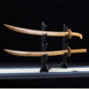 Two Chinese wooden saber swords of differing design, displayed on a small wooden sword-stand.