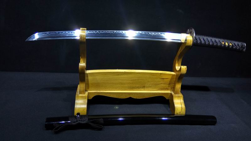 One Handed Japanese Sword A one handed Japanese sword Wakizashi, displayed on a wooden sword-stand, with its black scabbard below on the floor.