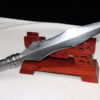 A double edged spear head leaning against a small wooden stand.