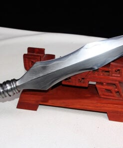A double edged spear head leaning against a small wooden stand.