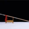 A Chinese double edged, collapsible spear, leaning against a wooden stand.