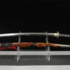 A red dragon Katana sword displayed next to its decorative scabbard, on a small plastic sword-stand.