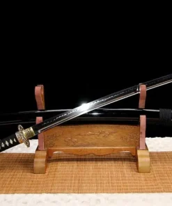 A black dragon sword and its scabbard, displayed on a small wooden stand.