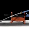 A real demon destroyer sword Katana, displayed next to its scabbard, on a small wooden stand.
