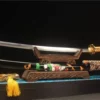 A beautiful Katana sabre displayed next to its decorative scabbard, on a small wooden stand.