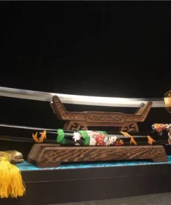 A beautiful Katana sabre displayed next to its decorative scabbard, on a small wooden stand.