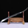 A saber one piece sword, displayed leaning against a small wooden stand.