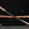 A WW2 Japanese sword Katana, displayed crossed against its scabbard, on a small wooden sword-stand.