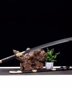 A Chinese sabre Taijidao displayed balanced on a small wood log, with its scabbard below on the floor.