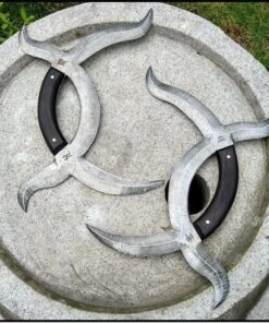 Two crescent moon blade knives displayed on a stone garden bowl.
