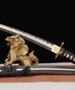 A dragon Tanto knife displayed leaning against a small statue, with its sheath below on the floor.