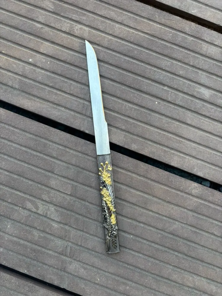 Kogatana A small Kogatana knife, displayed lying on wooden floorboards.