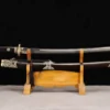 A Qing Dao sword saber, displayed next to its decorative scabbard, on a small wooden stand.