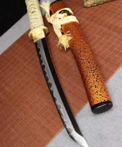A Tanto Japanese knife displayed next to its scabbard, lying on a bamboo mat.