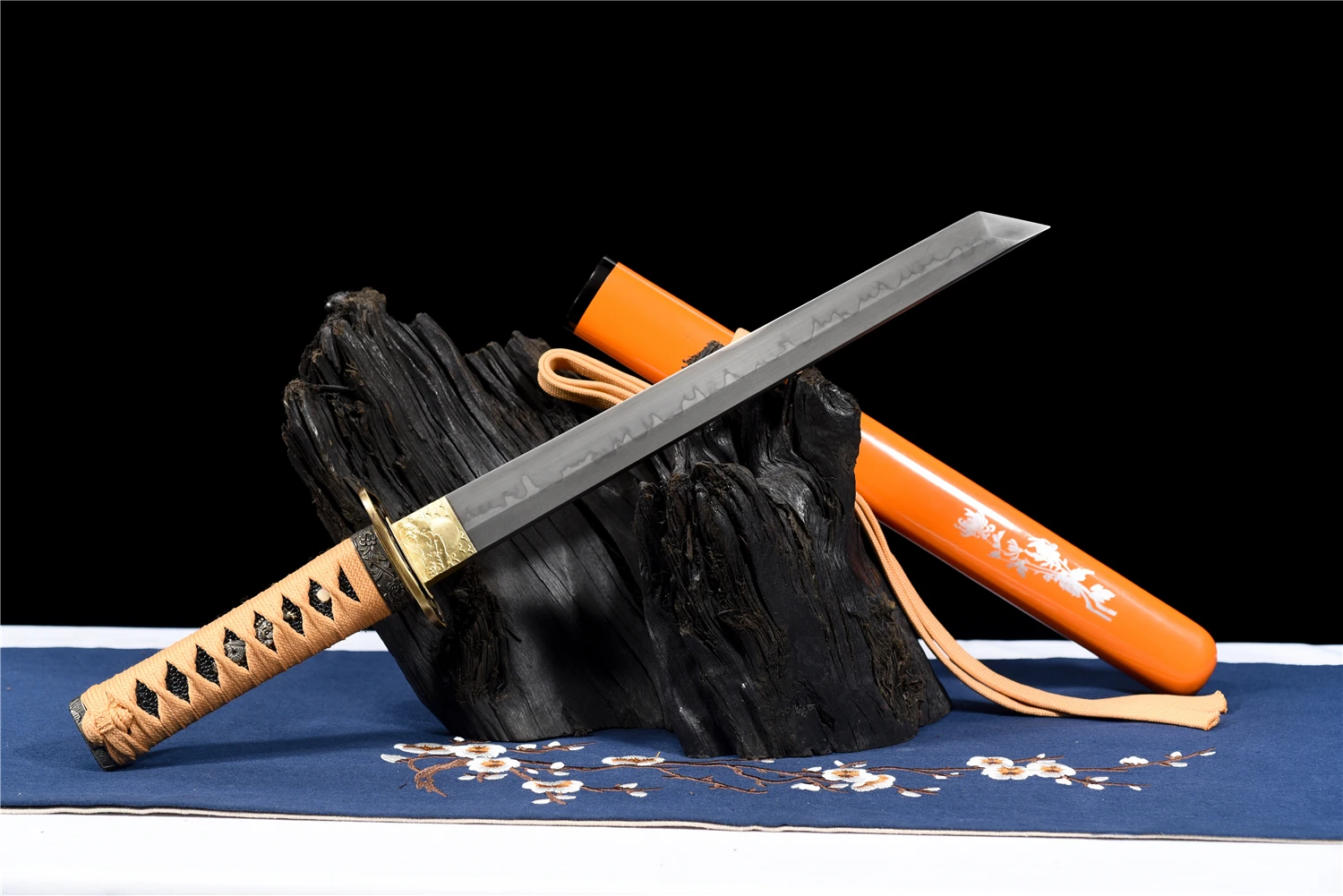 Tanto Sword A Japanese Tanto sword and its scabbard, displayed leaning against a small wood log.