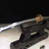 A Japanese Tanto weapon displayed on a small wooden stand.