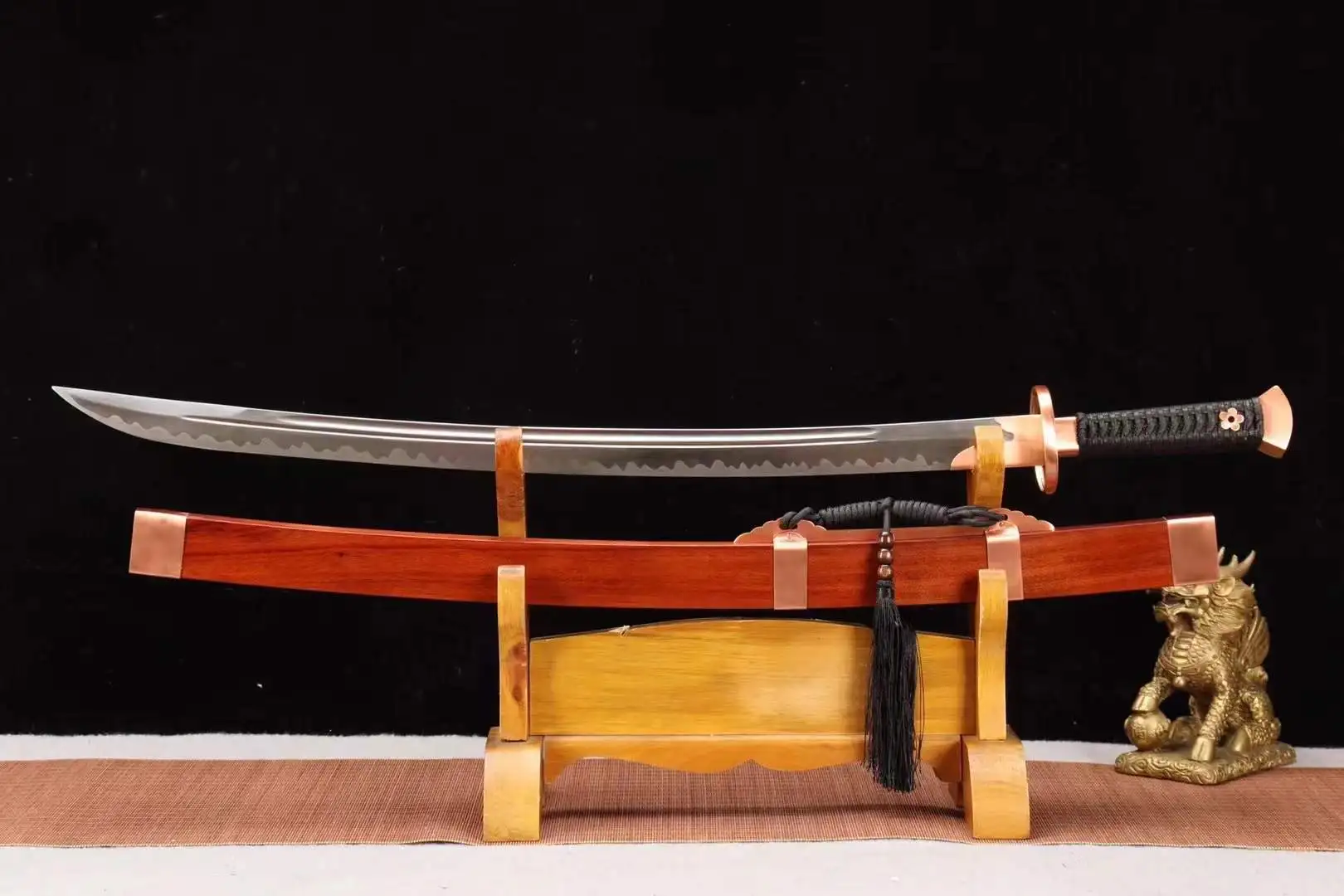 Yaodao A Chinese Yaodao sword, displayed next to its scabbard, on a small wooden stand.