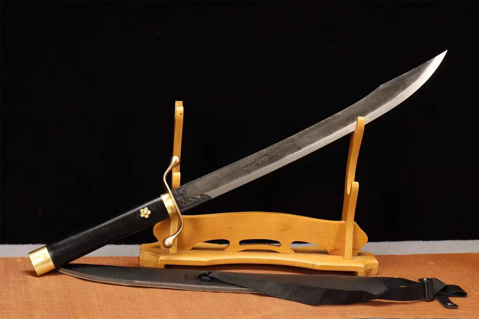 Short Curved Sword A short curved sword saber, displayed leaning against a small wooden stand, with its scabbard below on the floor.