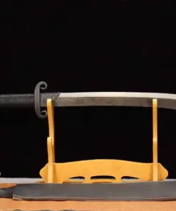 A short saber sword displayed on a small wooden stand, with its scabbard below on the floor.