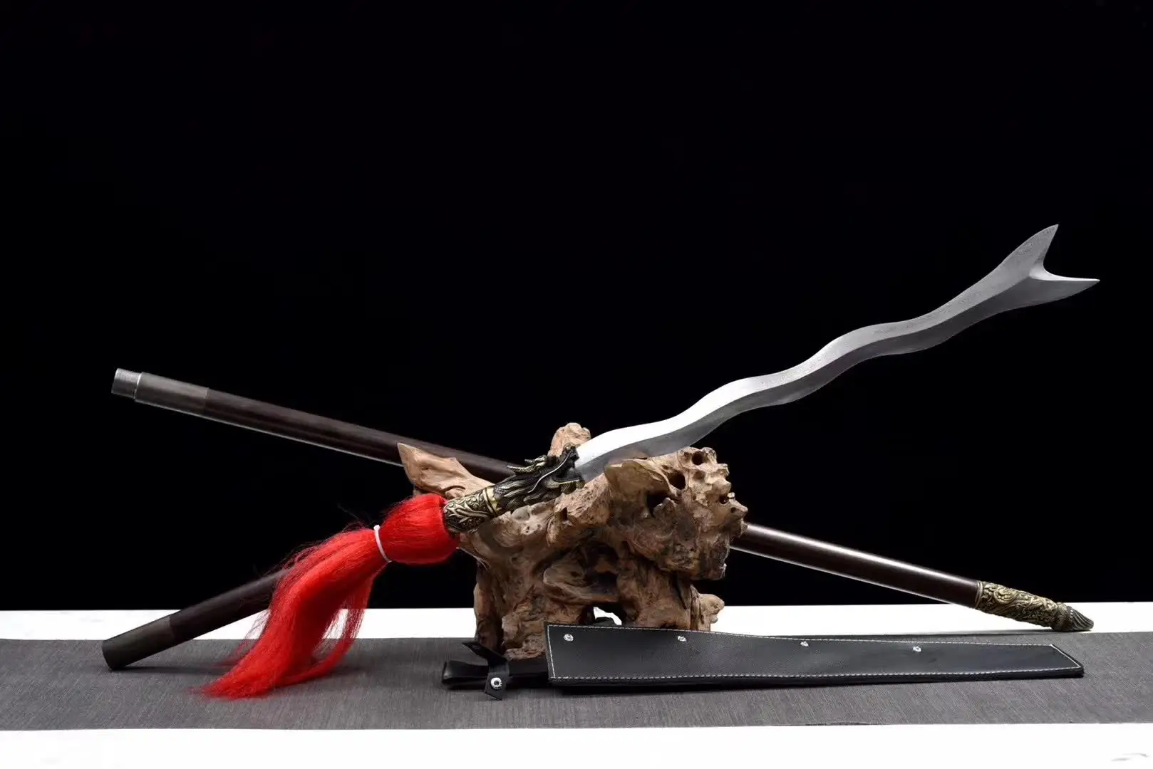 Snake Spear A sepent snake spear displayed next to its pole handle extension, leaning against a small wood log.