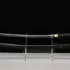A Katana black sword displayed next to its scabbard, on a small stand.