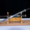 A Han Jian sword displayed next to its traditional scabbard, leaning against a small wooden stand.