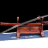 A sword made with the sharpest Katana Wootz steel, displayed next to its scabbard, leaning against a small wooden stand.