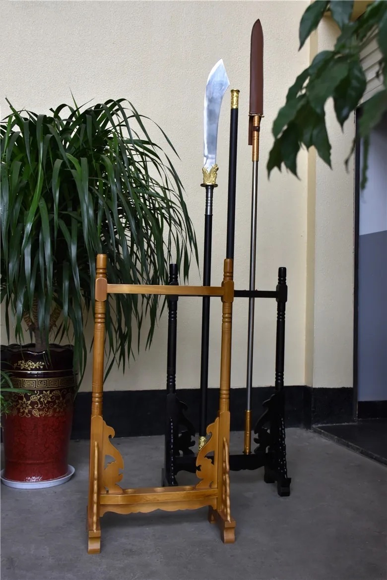 Weapon Stand A gold colored weapon stand, with a black colored spear stand behind, holding three Chinese polearm weapons.