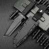 A black tactical Tanto knife displayed next to its sheath.