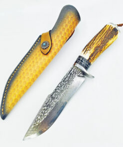 A Damascus survival knife displayed nest to its leather sheath.