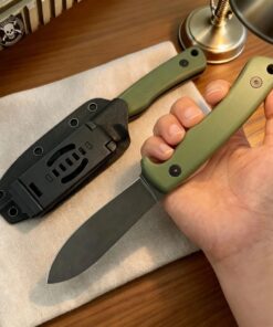 A mans hand holding a Nessmuk pig skinning knife, with the same knife shown sheathed, lying on a table.