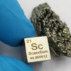 A pure scandium metal cube displayed next to its natural mineral ore.