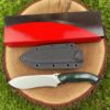 A fixed blade survival hunting knife, displayed next to its Kydex sheath and box on a tree stump.
