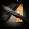 A large survival knife, displayed lying against its sheath.