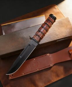 A marine usmc knife displayed next to its leather sheath and box.