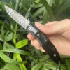 A Man's hand holding a bone handle Damascus pocket knife.