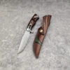 A Damascus steel hunting knife, displayed next to its leather sheath.