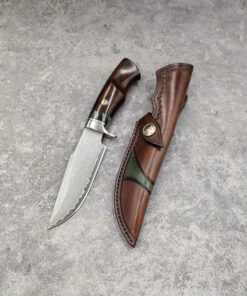 A Damascus steel hunting knife, displayed next to its leather sheath.