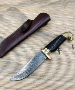 A Damascus steel skinning knife, displayed next to its leather sheath.
