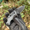 A man's hand holding a small folding pocket knife.