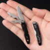A man's hand holding a small travel knife.
